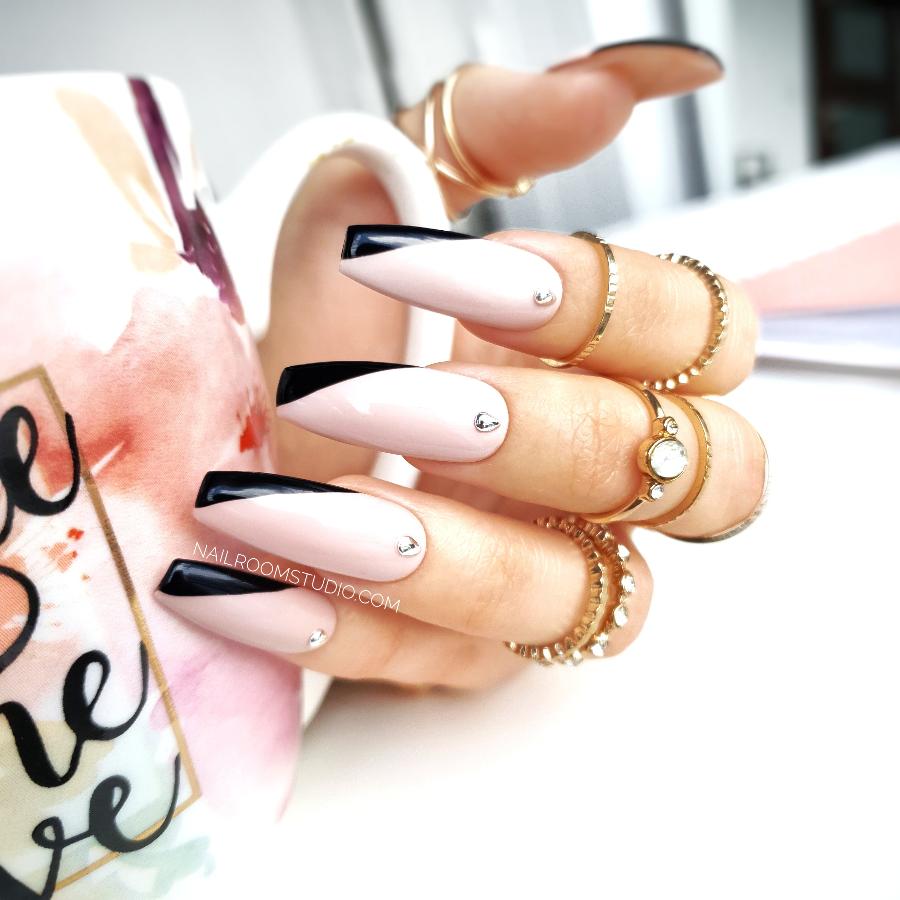 Beautiful glossy nude press-on nails adorned with silver accents and unique angled black french tips, ideal for chic looks and shipped worldwide