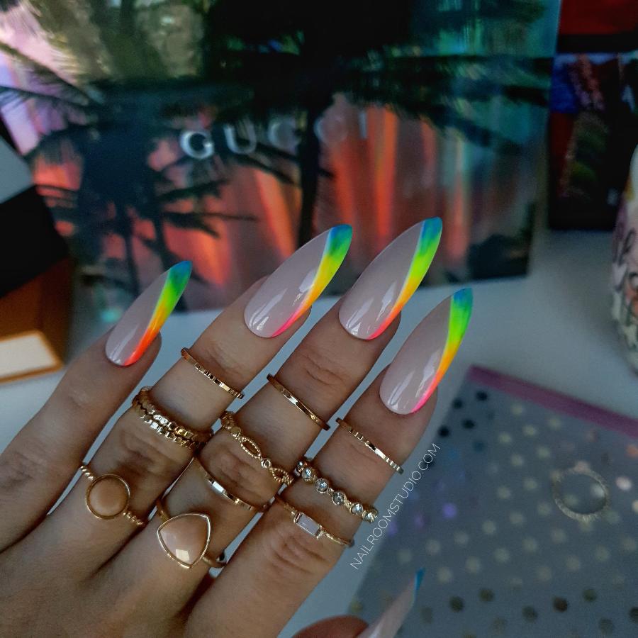 Nude nails with a vibrant rainbow diagonal French design showcasing shades of yellow green pink orange and red for a colorful and modern twist on classic nails