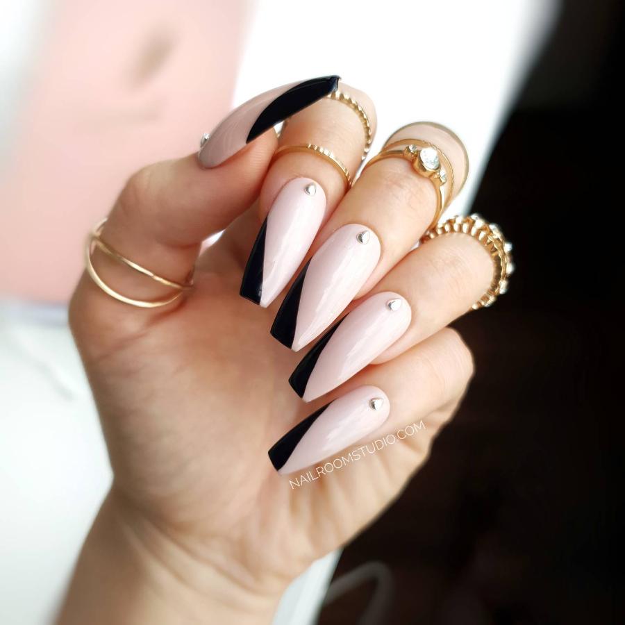 Shiny nude press-on nails with silver accents on each nail and a fancy angled black French tip, showcasing international shipping options