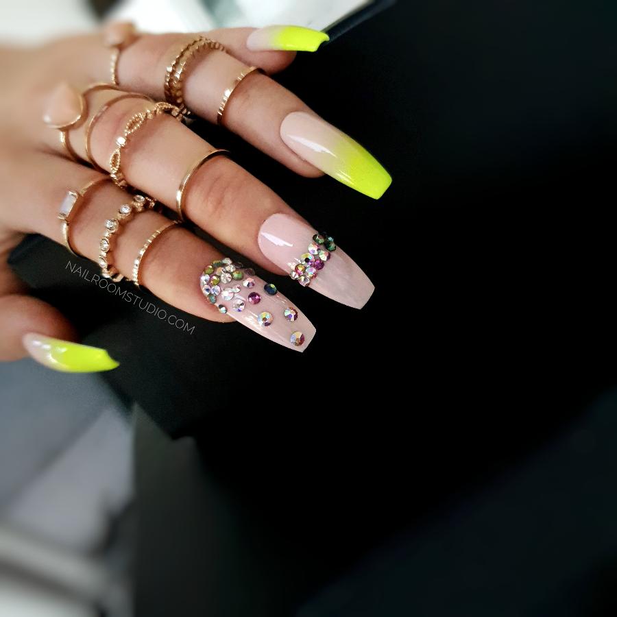 Soft nude nails with a bright yellow neon ombre and colorful Swarovski crystal accents for a lively and fresh look