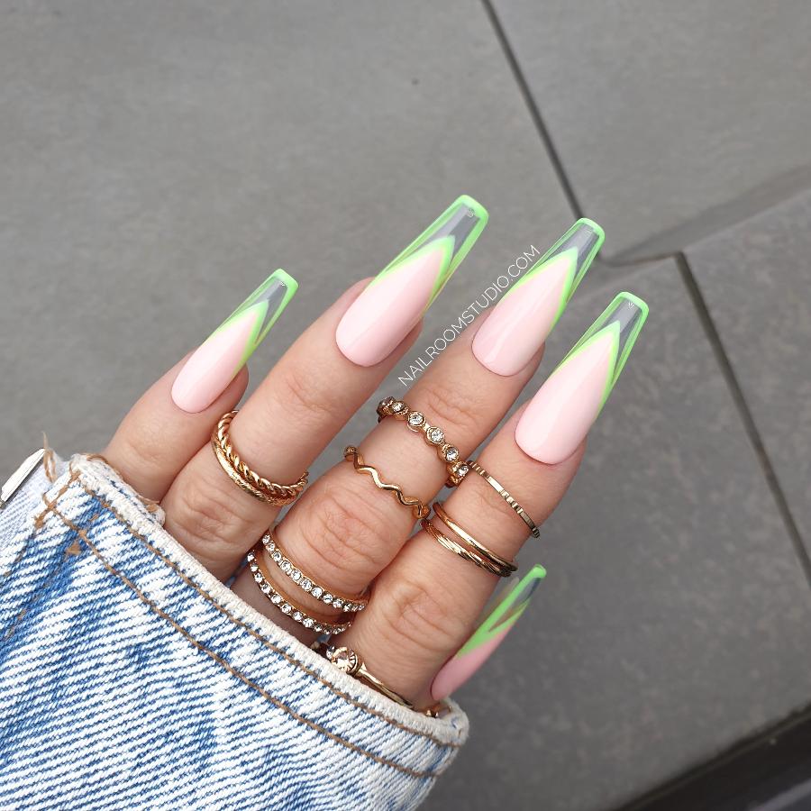 French nails in soft pink with neon green tips and a clear modern design, presented with jewelry on the fingers