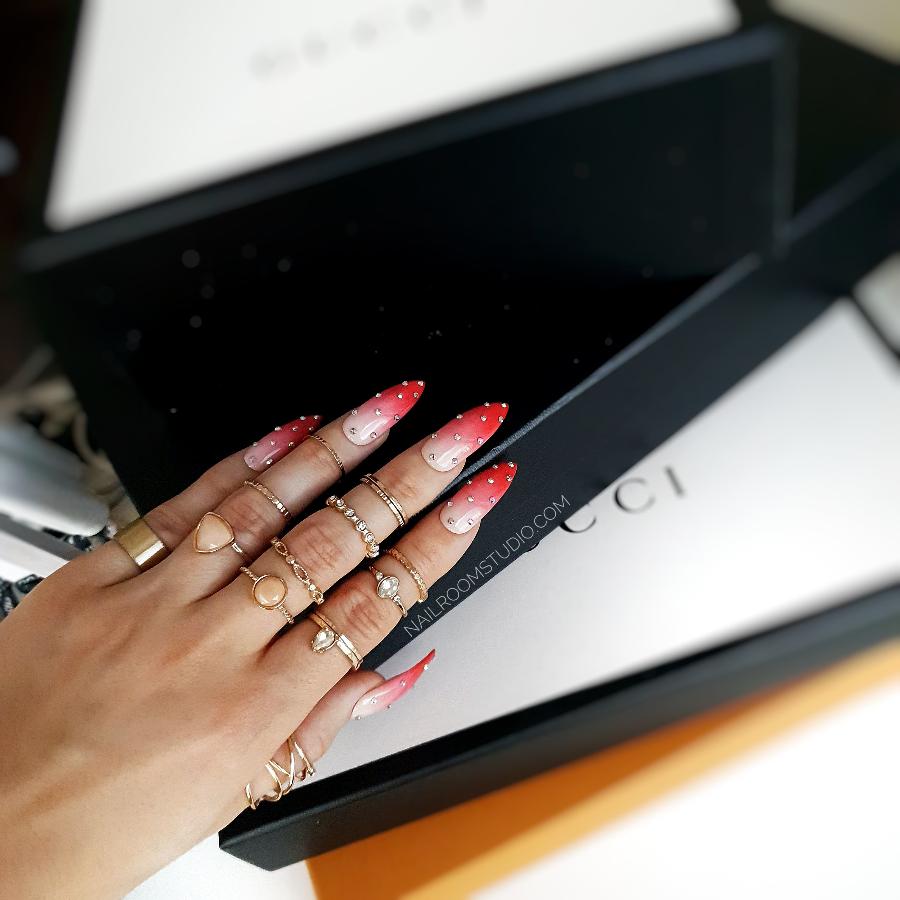 Pink and red ombre strawberry nails adorned with sparkling silver Swarovski crystals for a glamorous summer look