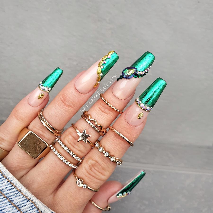 Glamorous Press-On nails with chrome French tips, adorned with Swarovski crystals and gold accents, displayed on a hand with long coffin nails