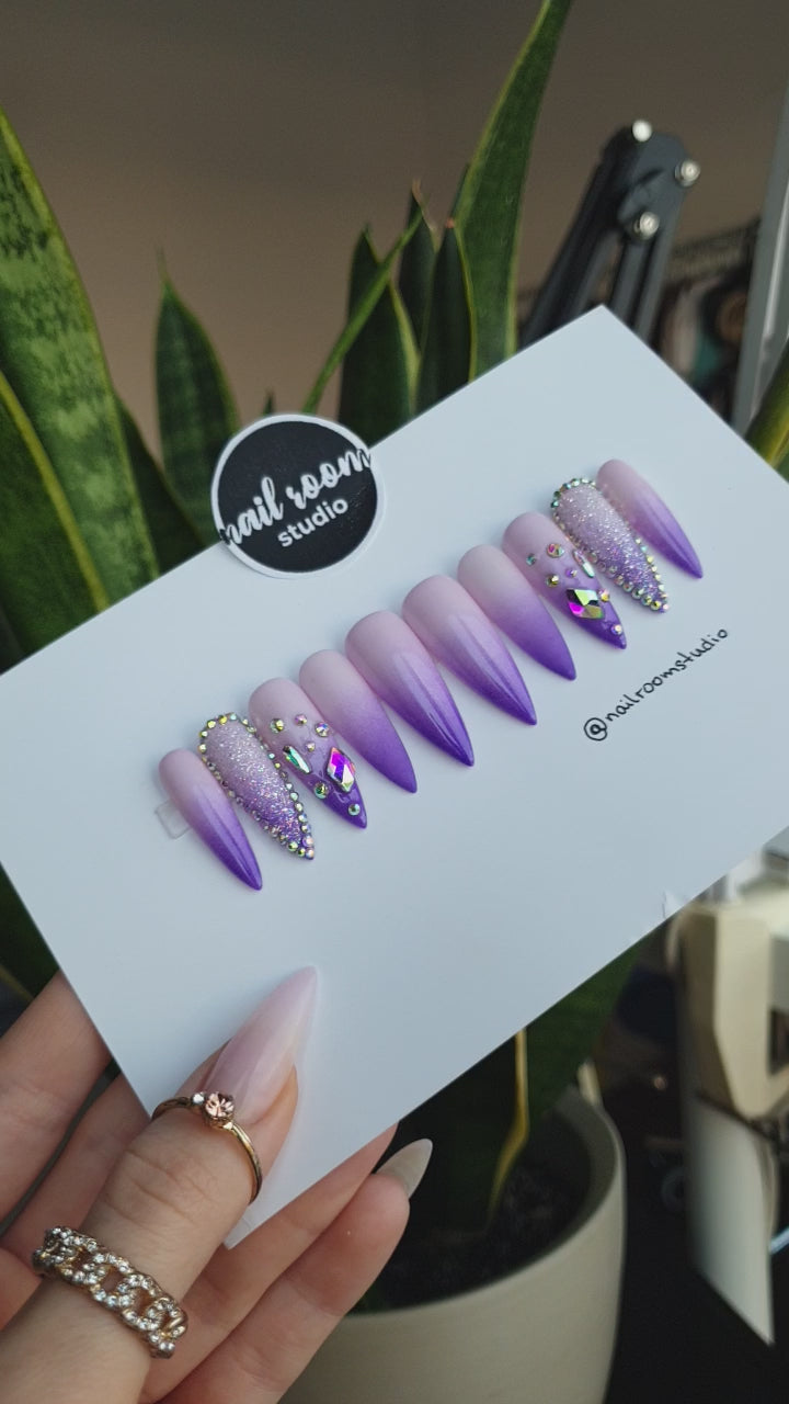 Elegant purple press on nails featuring a gradient ombre effect with lilac tips and crystal embellishments, available in various sharp sizes