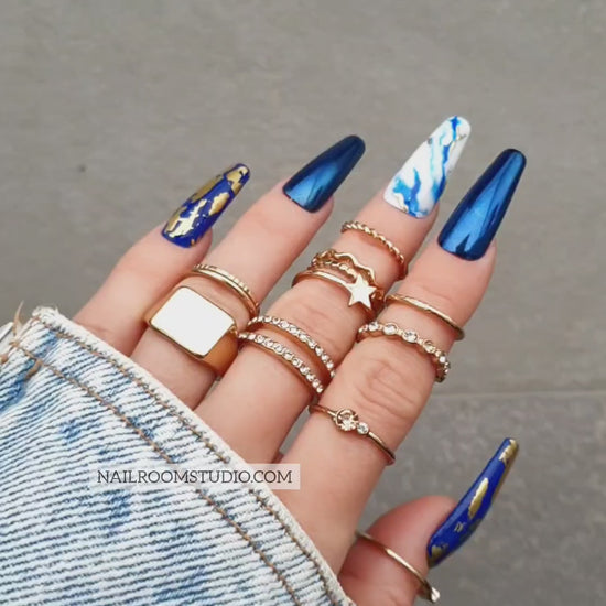 Navy blue chrome faux nails with gold chrome accents and hand-painted blue and white marble designs, available in all sizes