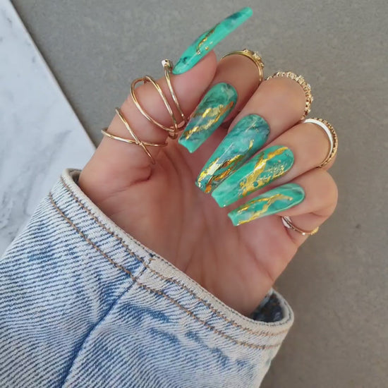 Long coffin-shaped nails for toes and hands with glue by Nail Room Studio in green with gold chrome accents, marble patterns, and water-painted details for a rich autumn style