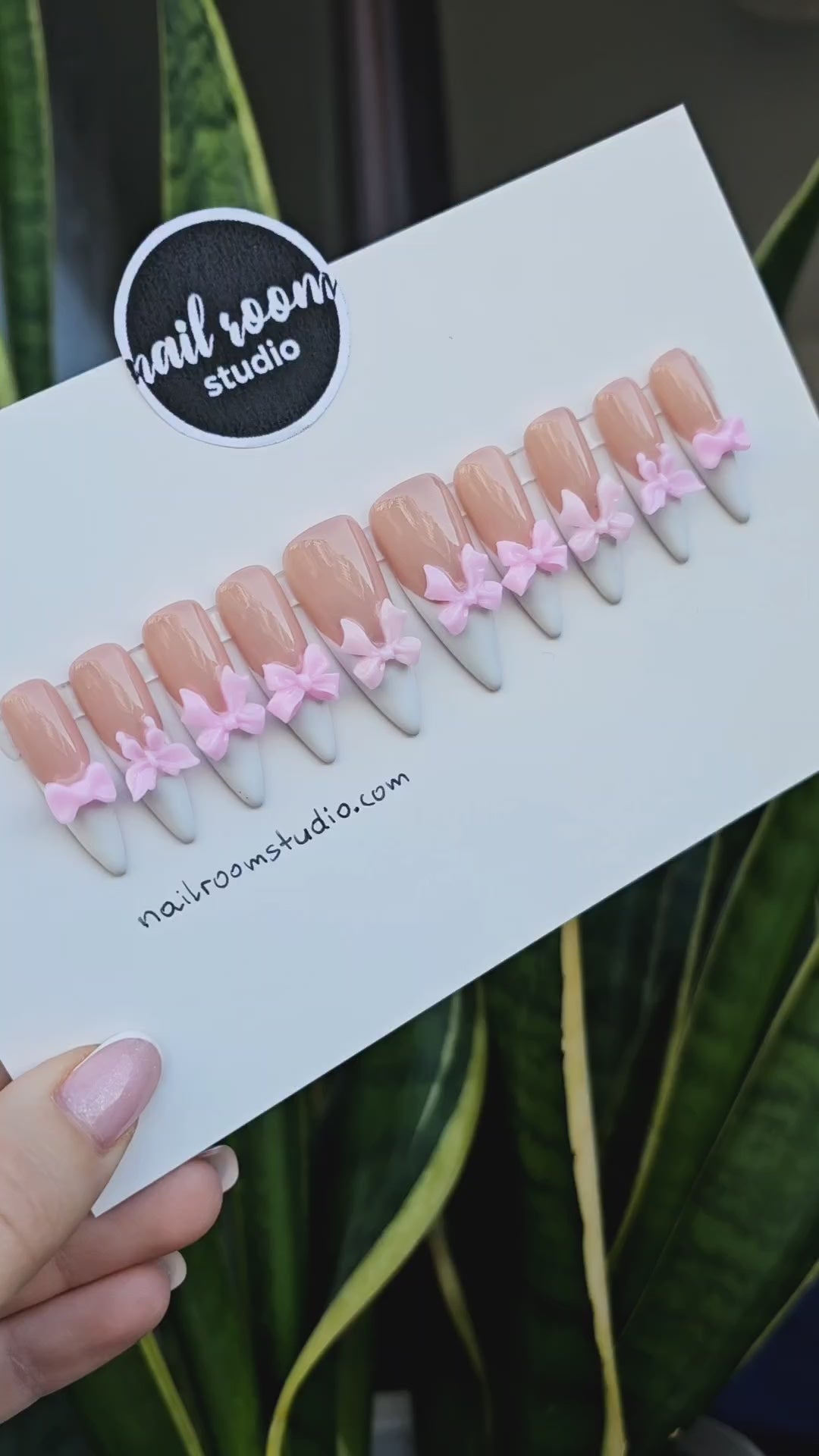 Adorable nude press on nails featuring sharp sculpted stiletto shapes and charming 3D pink bows on each nail for a playful finish