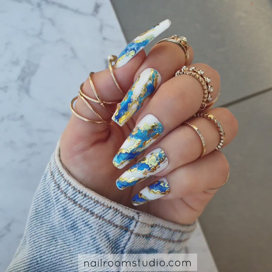 Exclusive navy blue nails by Nail Room Studio in long sculpted coffin shape with wavy design, gold chrome accents, and blue marble effect, available as matching mani-pedi set