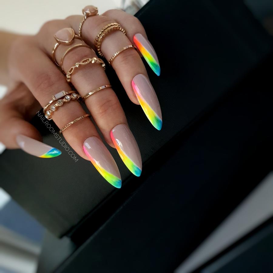 Elegant nude nails with an angled rainbow French tip featuring bold colors like yellow green pink and red adding a playful touch to a chic look