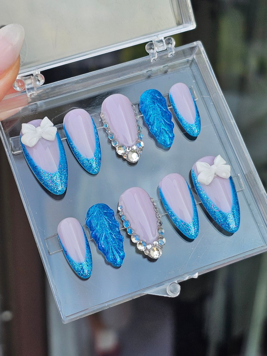 Blue shell style press on nails with mauve French tips, silver bow accent, glitter blue and Swarovski crystals, personalized and shipped worldwide.