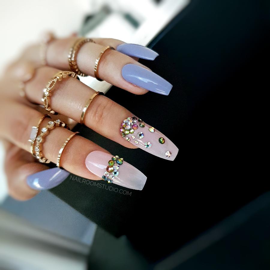 Elegant lilac nails paired with a delicate powder pink accent, embellished with colorful crystals for a sophisticated look