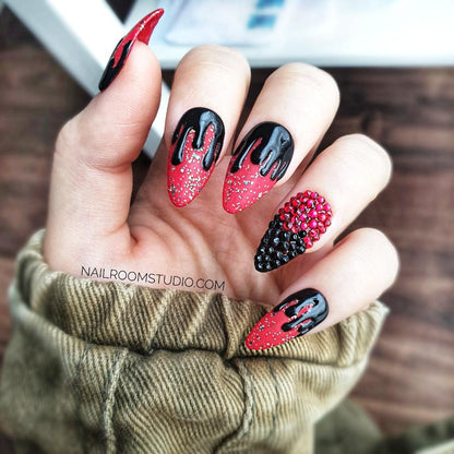 Deep red and black "witchy" Halloween-themed press-on nails with a glossy dripping effect resembling black blood or tar, one nail accented with dark red and black Swarovski crystals, shown on hands