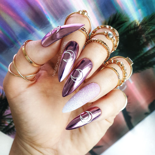 Long stiletto nails with glitter ombre and pink champagne moon accents, a bold witchy look with chrome highlights